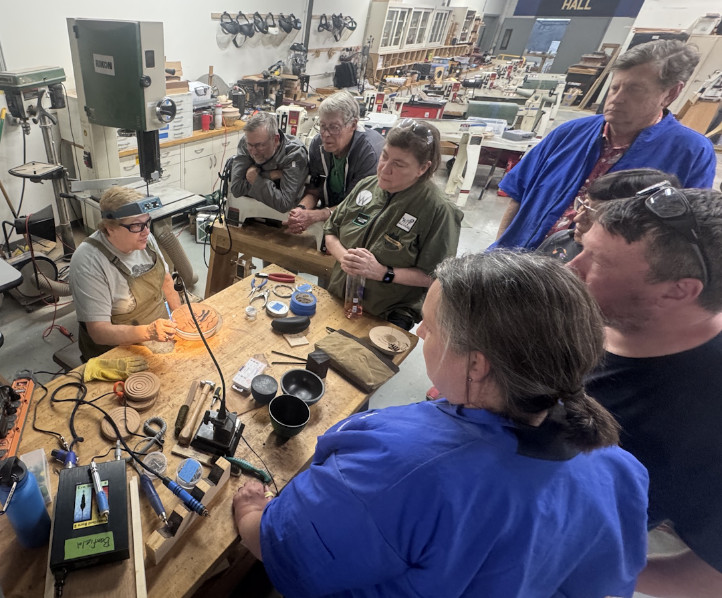 Chicago Woodturners members gathered around a bench watching a hands-on demonstration